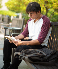 Photo of SUNY Plattsburgh student reading on a bench