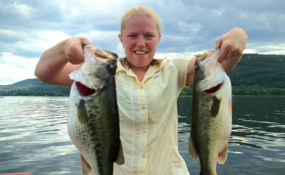 Photo of of Nikki Eddy holding 2 bass on a boat