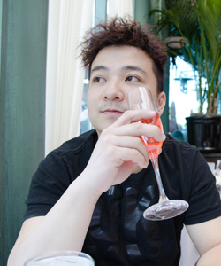 Portrait of Danny Chang sitting in a restaurant and drining a glass of wine