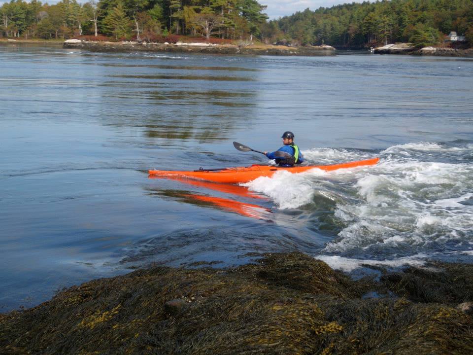 A student kayaks in the surf