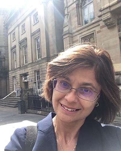 woman on an historic city street takes a selfie, sun shining from behind