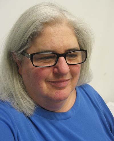 close up of woman with blue crew neck shirt looking slightly down and away