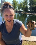 Portrait of Danielle Garneau holding up a musk turtle on the bank of Lake Champlain