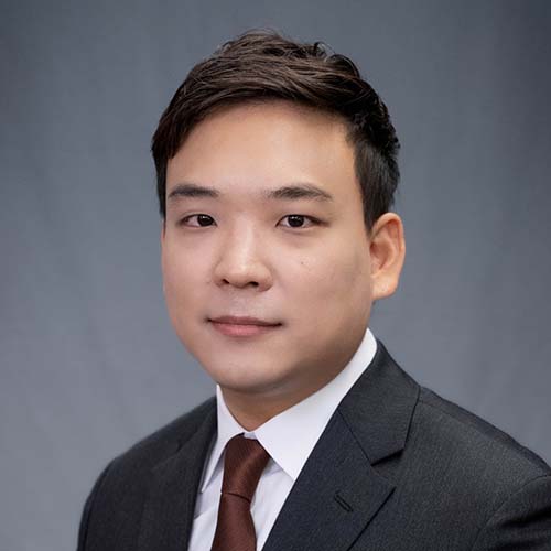 Man in a dark suit sits for a professional headshot.