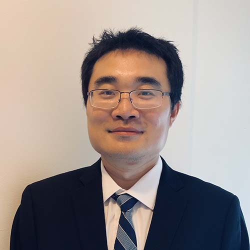 Dr. Wu headshot; man wearing glasses and a dark suit grinning for the camera