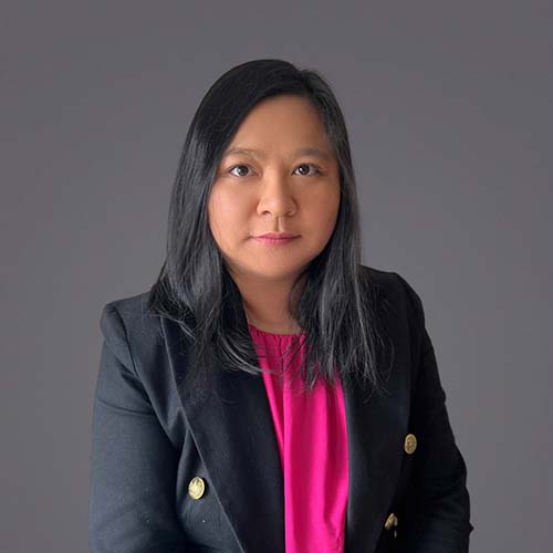 Woman with long dark hair sits for a professional headshot, wearing a navy-inspired blazer