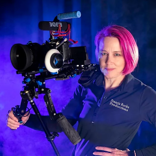 Woman stands in a dimly lit studio with a tv-video recorder camera