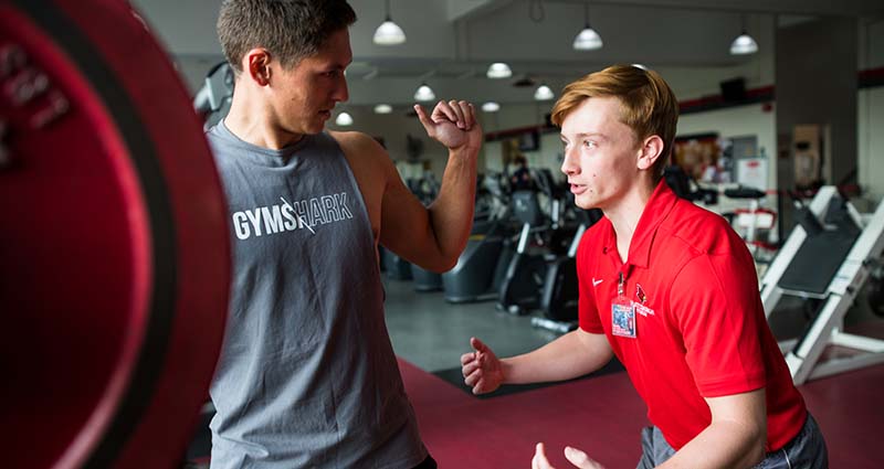 Personal trainer helping a male client with his weightlifting form