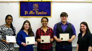 Photo of Namini De Silva, Samantha Rogers, Bezawit Woldegebriel, and Nicholas Harding holding their certificates while standing underneath the chapter banner