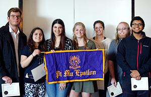 New members hold up the Alpha Xi chapter of Pi Mu Epsilon banner