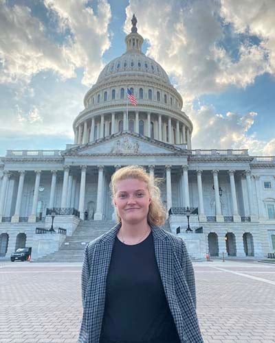 Student standing in professional attire in front of the Capitol building in Washington, D.C.