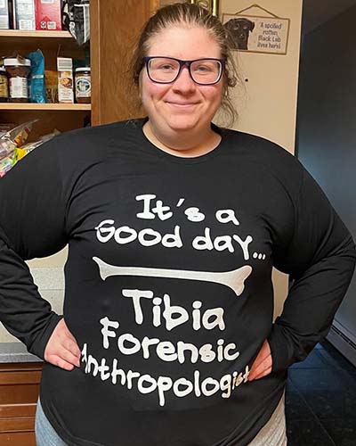 student standing displaying proudly a shirt with a pun: It's a Good day tibia forensic anthropologist