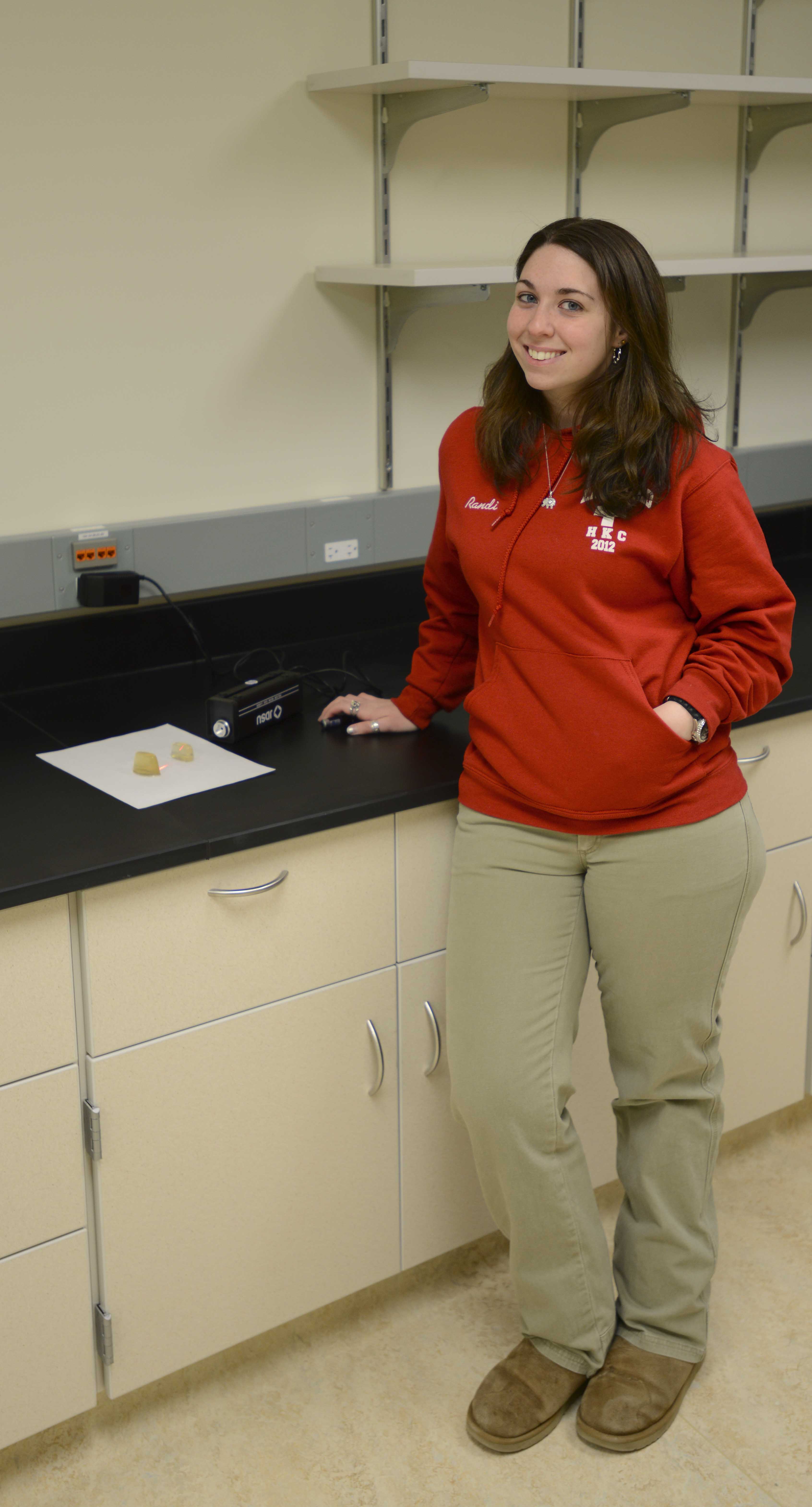 Randi stands next to notes on a work bench in a lab classroom