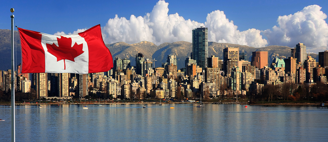 View of the Canadian flag flying in front of a Canadian city on a lake