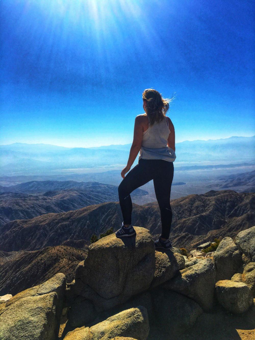 An NSE student on a hike looks out over mountainous terrain