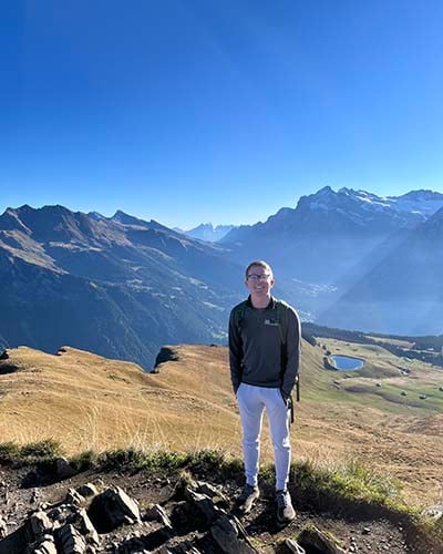 An NSE student poses in Oregon with mountains.