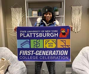 Anne Nelzy holds a banner that says, "State University of New York Plattsburgh First-Generation College Celebration"