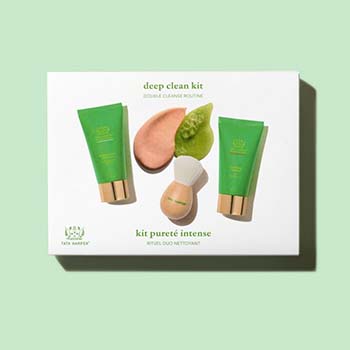 An upscale kit for facial cleansing products; two green and gold product tubes with a small lathering brush with a round wooden handle