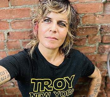 Artist selfie: at arm's length, looking up into the camera. Artist wears a shirt that says Troy New York in Star Wars font
