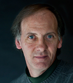 man with a black shirt against a black backdrop in a dramatic studio shot