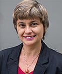 woman with red shirt and dark suit jacket smiles