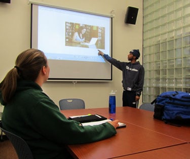 A student practices giving a presentation with a classmate