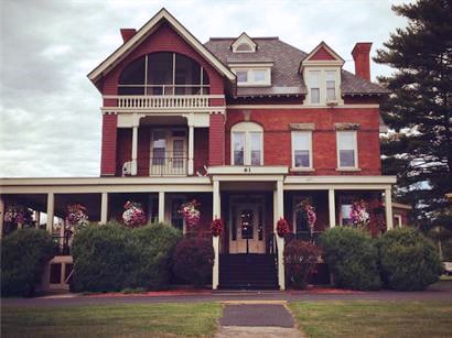 Samuel F. Vilas Home front porch, decorated with hanging flower baskets on an overcast day